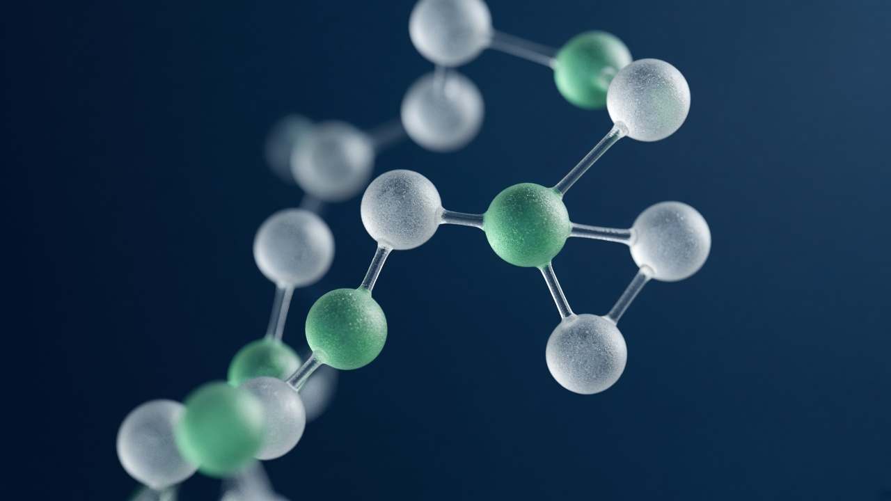 Abstract molecular model in frosted glass with a few green spheres, on a deep navy background